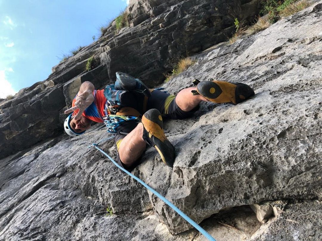 Arrampicatore sulla Via Adagio al Piccolo Dain in Valle del Sarca tra placche verticali e tetti di roccia calcarea